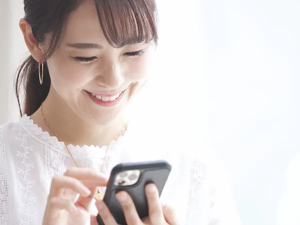 スマートフォンで予約する女性のイメージ